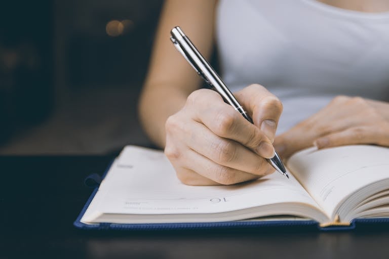 Woman writing in a notebook, capturing a moment of focused concentration.